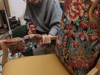 Stagiaire travaillant sur la réfection d’un fauteuil, dans le cadre d’une formation pour devenir tapissier