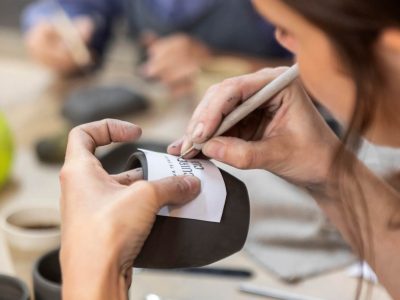 Main gravant un motif sur une tasse en argile lors d'une formation de tournage céramiste à Montpellier