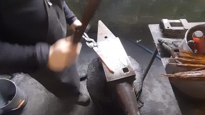 Pratique avec le marteau et l'enclume pendant le stage en coutellerie avec un coutelier