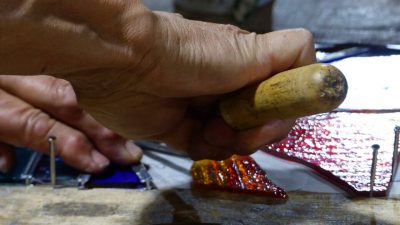 mains de stagiaire pendant le stage de vitrail avec un vitrailliste