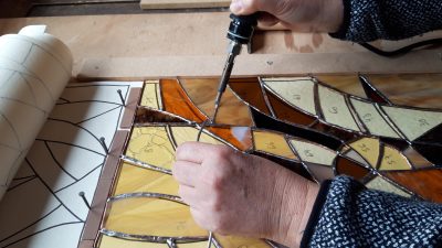 Soudure d'un vitrail pendant le stage et les cours de vitrailliste dans un atelier dans le Perche