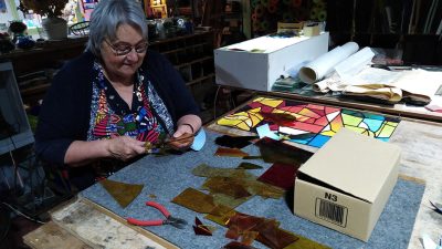 Stagiaire à la coupe de verre pendant le stage de vitrail avec une vitrailliste
