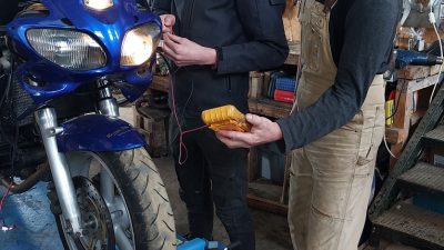 Samuel Do qui transmet son savoir en électricité autour d'une moto pendant le stage